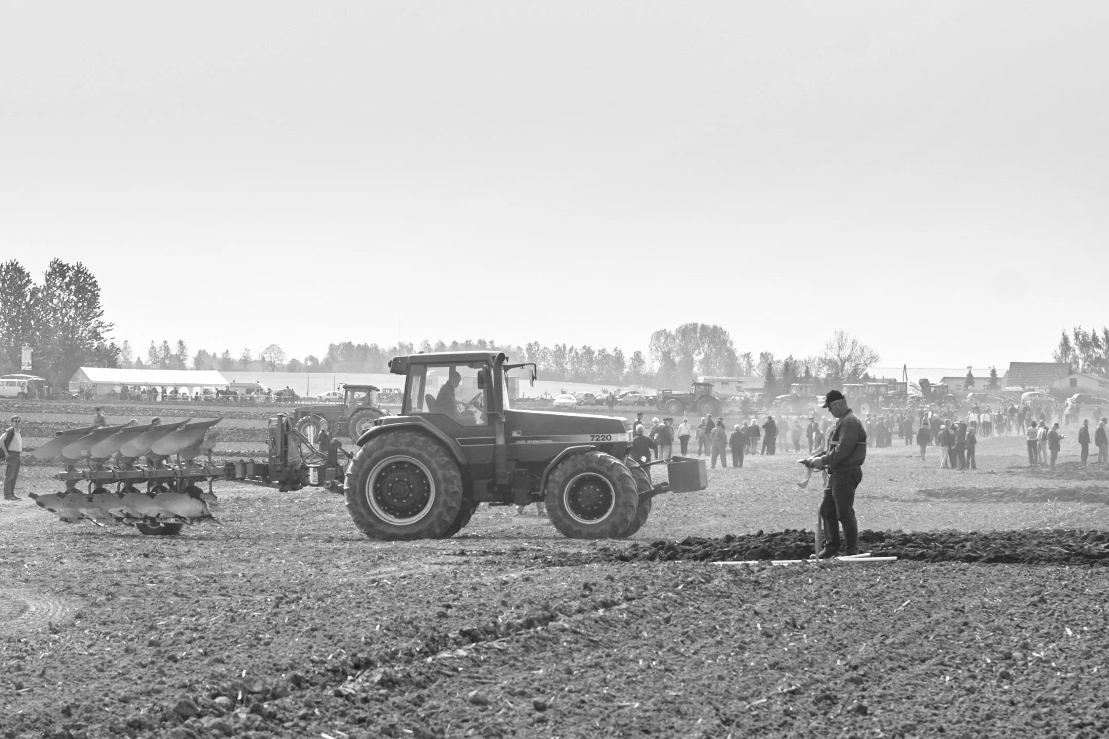 Landwirtschaftliche Vorführung mit Traktoren und Pflug auf einem Feld.