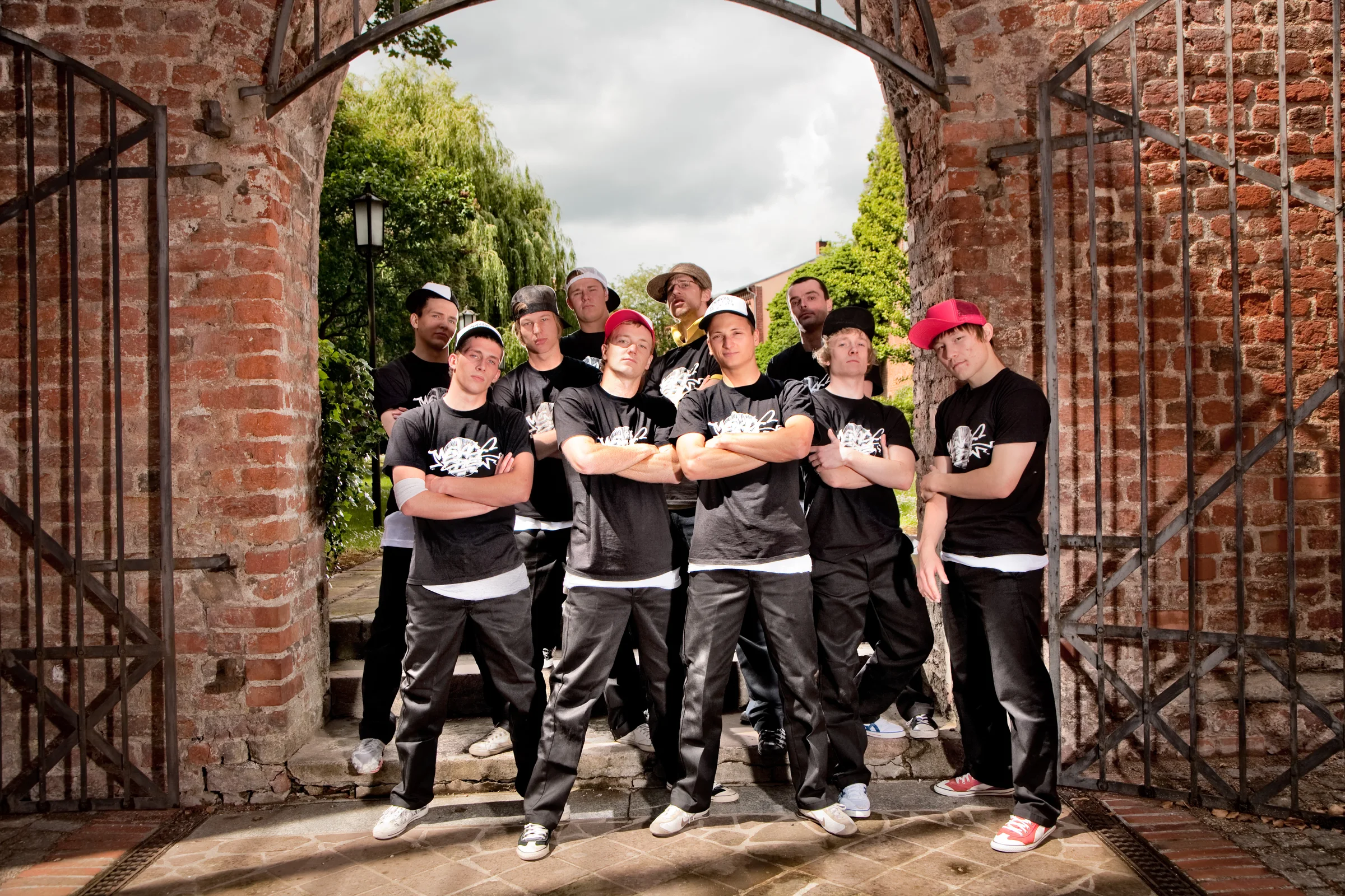 Eine Gruppe Breakdancer posiert gemeinsam in einheitlicher Kleidung vor einem historischen Backsteintor.