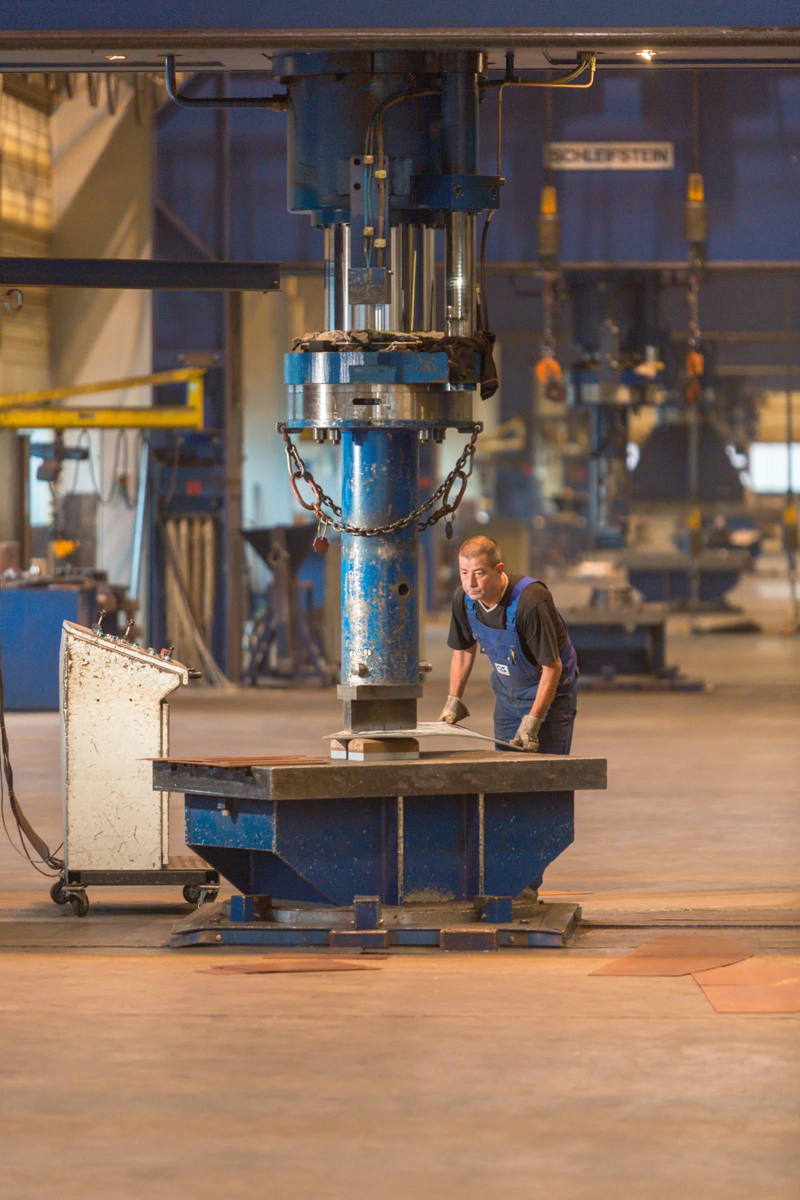 Ein Mitarbeiter arbeitet an einer großen Umformmaschine in einer Produktionshalle.